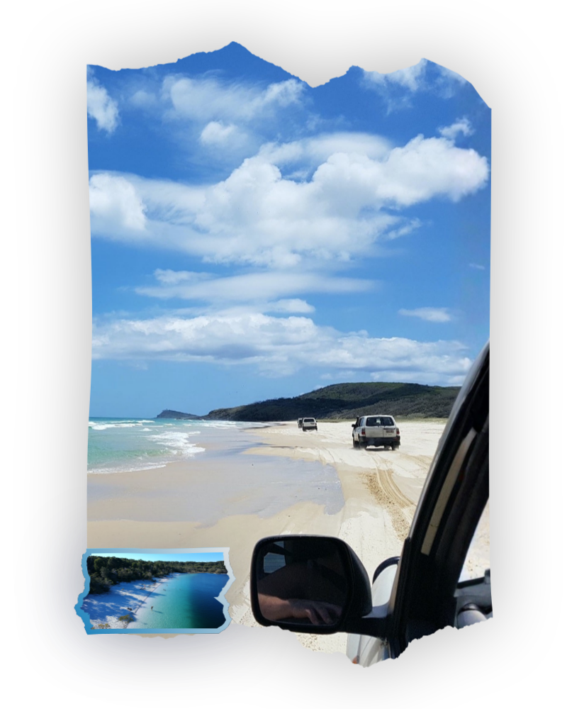 Vehicles driving on a sandy beach under a blue sky with clouds.